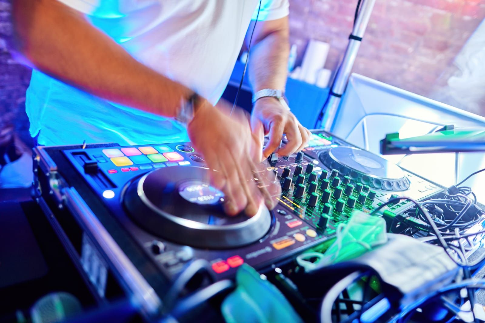 Hände an einem professionellen DJ-Controller mit beleuchteten Bedienelementen