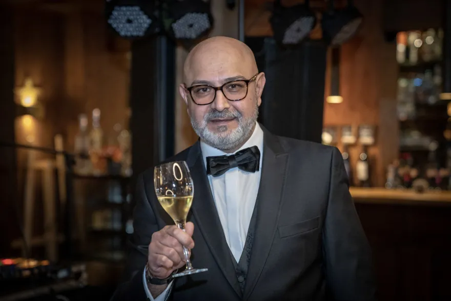 Chico im dunklen Anzug mit Fliege und einem Sektglas